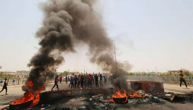 Iraqi protesters burn tyres and block the road at the entrance to Basra on Thursday.