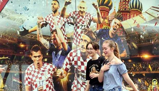 Two girls walking in front of a bilboard featuring Croatia's players in Zagreb on Thursday, a day after Croatia defeated England in a World Cup semi-final.