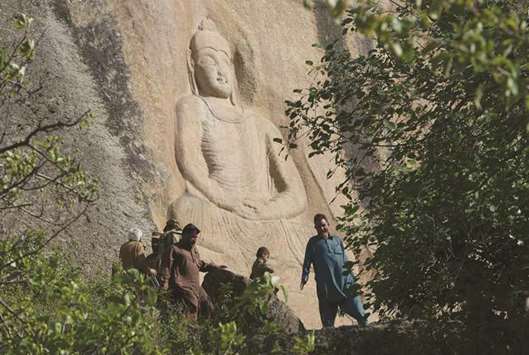 This photo taken on April 26, shows visitors near a 7th century rock sculpture of a seated Buddha, carved into a mountain in Jahanabad town in the northwestern Swat Valley of Pakistan, following a restoration process by Italian archaeologists after the Taliban  defaced it in 2007.