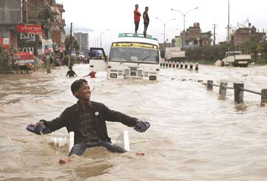 A Nepali boy smiles as he uses an improvised raft to manoeuvre through the floodwater after incessant rainfall in Bhaktapur.