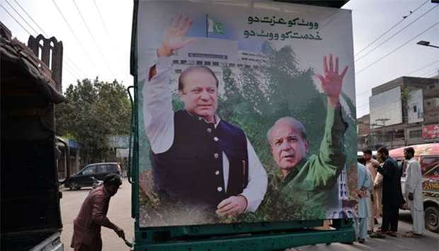 A worker paints a truck with a billboard featuring images of Nawaz Sharif and his younger brother Shahbaz Sharif. Shahbaz will lead a rally towards Lahore airport ahead of the arrival of Nawaz from London on Friday.