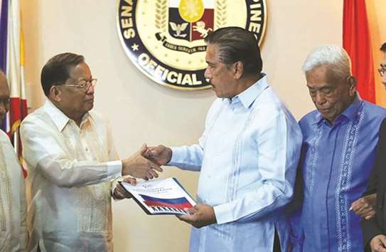 Former Chief Justice Reynato Puno hands over a copy of the draft federal charter to Senator Vicente u2018Titou2019 Sotto at the Hall of Office of the Senate President in Pasay City, as former Senate president Aquilino Pimentel Jr, looks on.