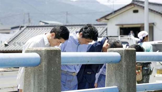 Japan's Prime Minister Shinzo Abe pays a silent tribute to victims of torrential rain at Nomura town in Seiyo on Friday.
