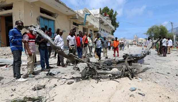 Civilians look at the wreckage of a vehicle near the presidential palace in Mogadishu on Saturday.