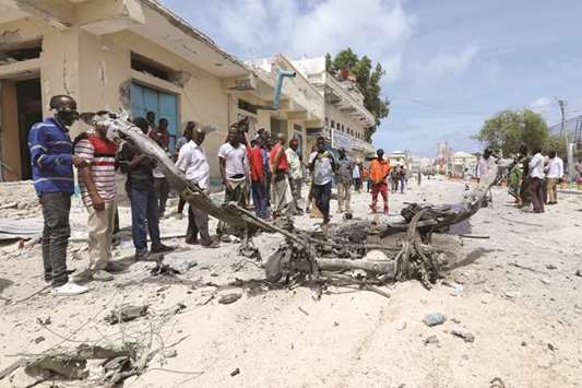 Civilians look at the wreckage of a vehicle destroyed at the scene where a speeding car exploded after it was shot at by police, outside the hotels near the presidential palace, in Mogadishu, yesterday.