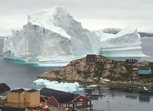 The giant iceberg is seen behind the Innaarsuit settlement.