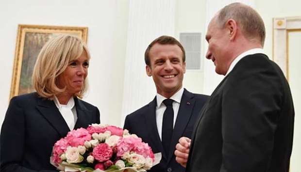 Russian President Vladimir Putin offers flowers to Brigitte Macron, wife of French President Emmanuel Macron, during their meeting at the Kremlin in Moscow on Sunday.