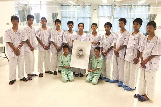 The 12-member u201cWild Boarsu201d soccer team and their coach rescued from a flooded cave pose with a drawing picture of Samarn Kunan, a former Thai navy diver who died working to rescue them at the Chiang Rai Prachanukroh Hospital, in Chiang Rai yesterday.
