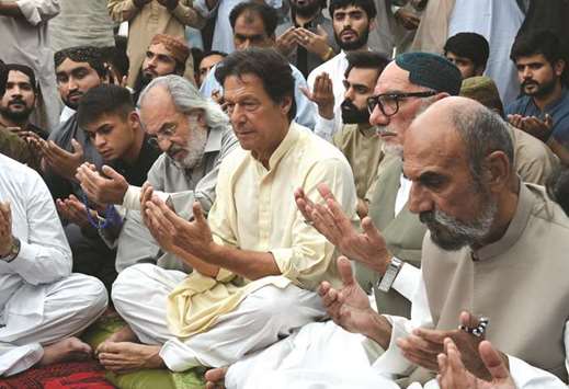 PTI chief Imran Khan, third left, prays with Aslam Raisani elder brother of Siraj Raisani, in Quetta yesterday.