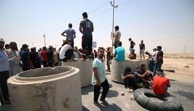 Iraqi protesters gather to block the road during a protest in south of Basra on Monday.