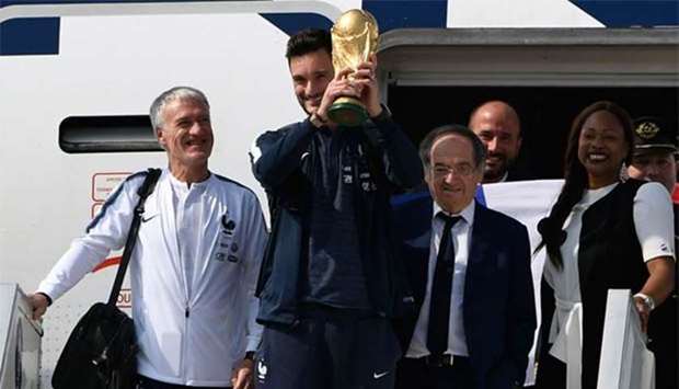France's goalkeeper Hugo Lloris holds the World Cup trophy as he disembarks from the plane next to France's coach Didier Deschamps, French Football Federation president Noel Le Graet (second right) and French Sports Minister Laura Flessel (right) upon their arrival at the Roissy-Charles de Gaulle airport in Paris on Monday.