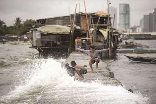 Children living on houses erected on the sea wall of Manila Bay play with waves caused by the tropical depression Henry that brought heavy rains in Metro Manila and the northern part of Luzon, yesterday.