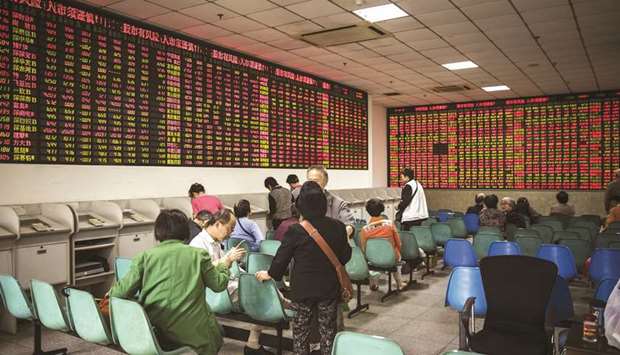Investors sit in front of an electronic stock board at a securities brokerage in Shanghai (file). Chinau2019s equity and bond markets are under pressure from a trade war and rising defaults, with the benchmark stock gauge sliding into a bear market last month and slipping again yesterday after data showed an economic slowdown.