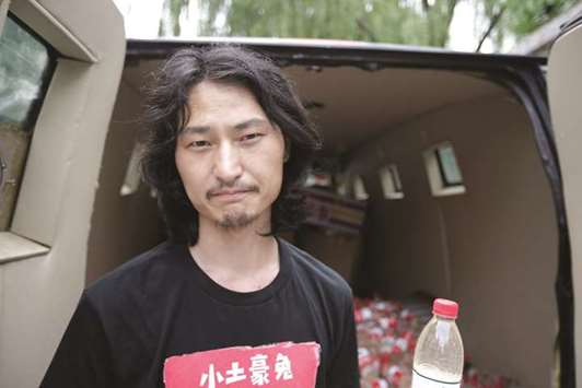 Chinese performance artist u201cBrother Nutu201d is seen with bottled polluted groundwater from Xiaohaotu county, Yulin of Shaanxi province, next to a mini van, which is used for a roaming exhibition.