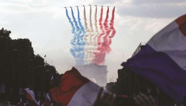 The Patrouille de France jets perform as they trail smoke in the colours of the French national flag while flying over the Arch of Triumph (Arc de Triomphe) near the Champs Elysee avenue as supporters welcome players of the French national football team in Paris yesterday.