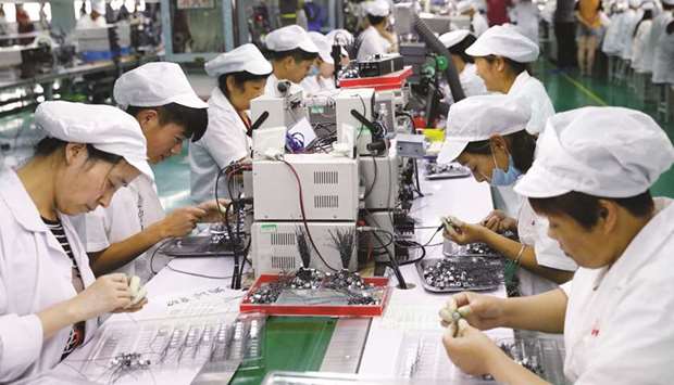 Employees working on a micro motor production line at a factory in Huaibei in Chinau2019s eastern Anhui province. Chinese growth slowed slightly in the second quarter as the worldu2019s number two economy faced a snowballing trade fight with the US.