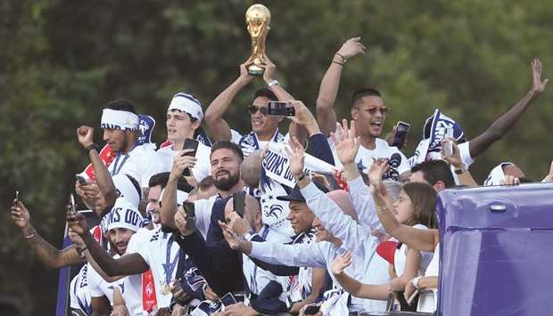 Franceu2019s defender Raphael Varane (C) holds the trophy as he celebrates with teammates on the roof of a bus while parading down the Champs-Elysee avenue in Paris yesterday.