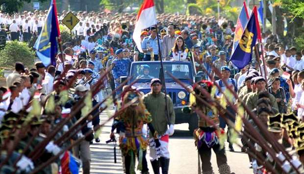 Centre L-R: Indonesia's Head of Air Force Yuyu Sutisna, Yogyakarta governor Sri Sultan Hamengku Buwono X, and Indonesia's former badminton player Susi Susanti lead a procession with the Asian Games flame in Yogyakarta.