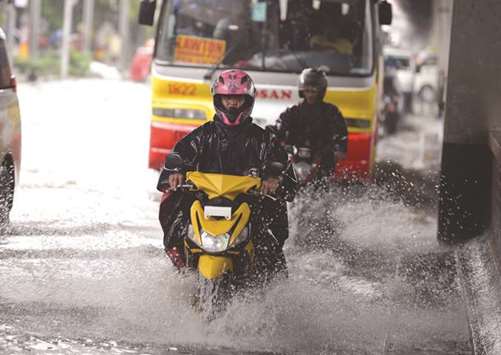 Motorists drive along a flooded street in Manila yesterday, as a tropical depression, locally named Henry, made landfall in northern Luzon island affecting suburban Manila and nearby provinces with monsoon rains.