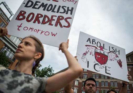 People hold up signs as they protest the US Immigration and Customs Enforcement agency and the recent detentions of illegal immigrants in Washington, DC.