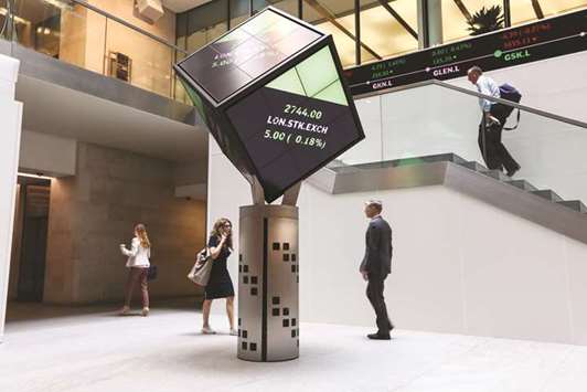 Visitors walk past an illuminated rotating cube displaying share price information at the London Stock Exchange (file). The FTSE 100 closed up 0.7% to 7,676.28 points yesterday.