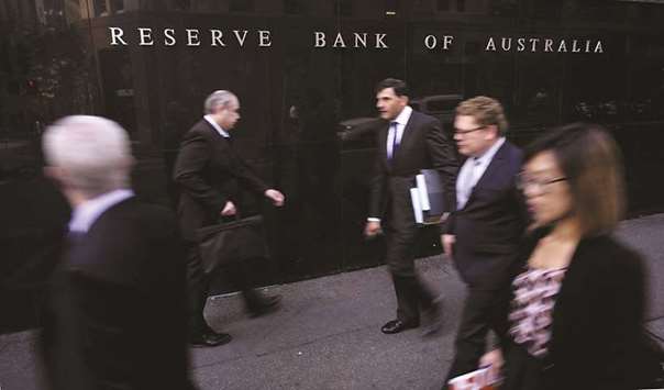 Business people walk outside the Reserve Bank of Australia in Sydney. The central bank predicts the Australiau2019s economy will expand at a 3%-plus pace this year and next, but also concedes that dangers are mounting.
