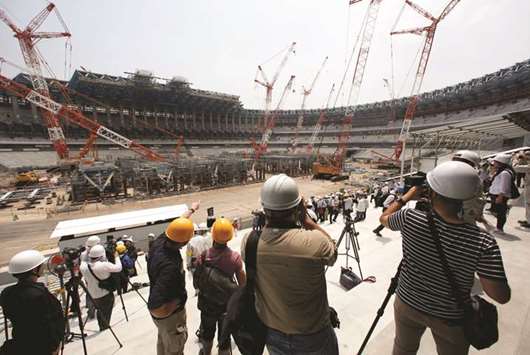 Workers and members of the media are seen at the construction site of the New National Stadium in Tokyo, Japan, yesterday. (Reuters)
