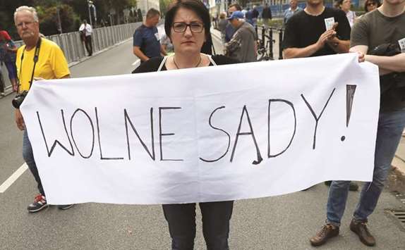 Woman holds a banner reading u2018Free Courtsu2019 as she takes part in an anti-government protest in support of free courts outside the Parliament building in Warsaw yesterday.