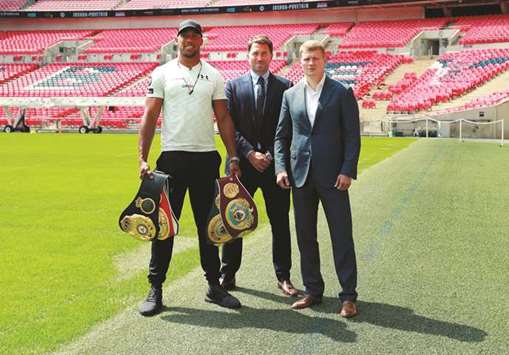 Boxers Anthony Joshua (left) and Alexander Povetkin (right) pose with promoter Eddie Hearn in London on Wednesday. (Reuters)
