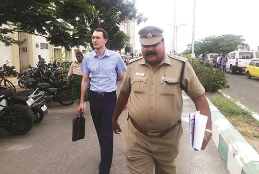 A Russian official is escorted by a policeman as they walk to visit the Russian tourist who was allegedly drugged and gang-raped in a service apartment during her visit to Tiruvannamalai.