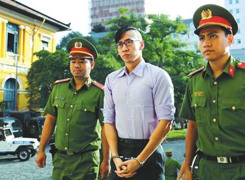 Will Nguyen, centre, is escorted by policemen before his trial at a court in Ho Chi Minh City yesterday.