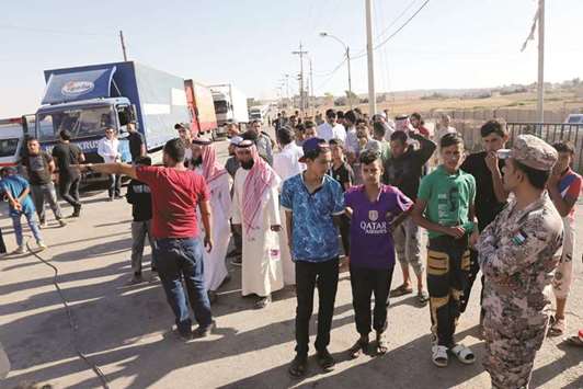 People gather while trucks loaded with humanitarian supplies to be delivered for displaced Syrians, wait at the Jordanian city of Mafraq, near the border, yesterday.