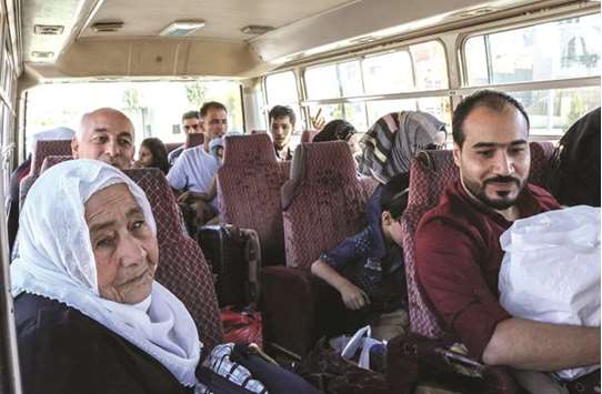 Syrian refugees ride in a bus evacuating them from Lebanon at the Masnaa crossing on the border yesterday, on their way back to Damascus.