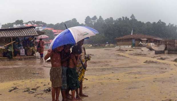 Rohingya refugee children shelter under an umbrella during a rain storm at Balukhali refugee camp in Ukhia.