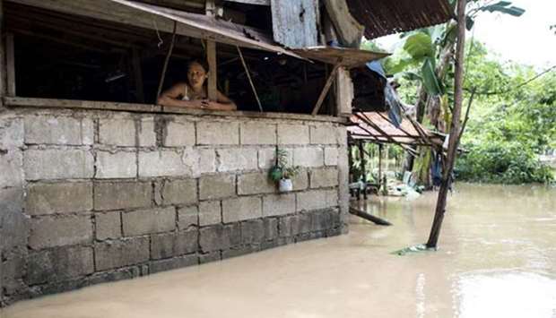 A woman looks out of her home as the Marikina river swelled after rain caused by Tropical Storm Inday (Ampil) in Manila on Friday.