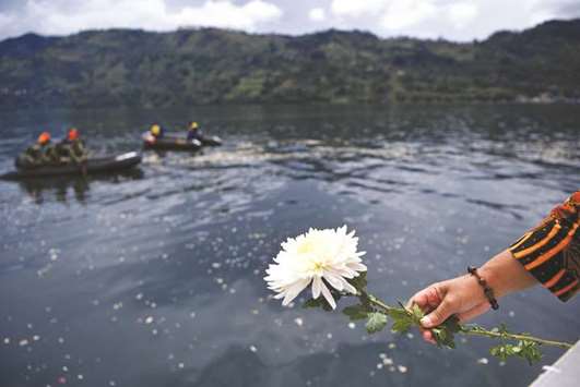 A relative of missing passengers of a ferry that sank holds a flower before throwing it into Lake Toba in Simalungun, North Sumatra, Indonesia.