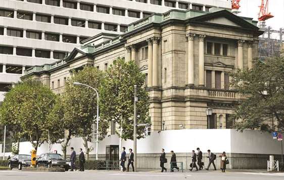 Pedestrians cross a road in front of the Bank of Japan headquarters in Tokyo. As the clock counts down to the BoJu2019s July 31 policy announcement, officials are looking for ways to keep their stimulus programme sustainable while reducing the harm it causes in markets and on the profitability of commercial banks.