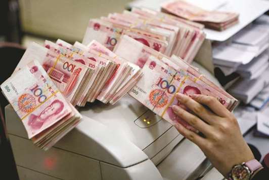 A clerk at a branch of the Bank of China counts yuan notes in Beijing (file). As Chinau2019s officials determine whether to respond to Trumpu2019s yuan manipulation charge, economists say there are clear arguments for a cheaper Chinese currency, justifying the current weakness.