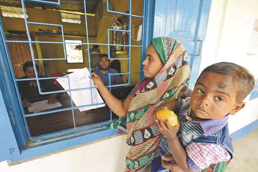 A woman carrying her son arrives to check her name on the draft list of the National Register of Citizens at an NRC centre in Chandamari village in Goalpara district of Assam.