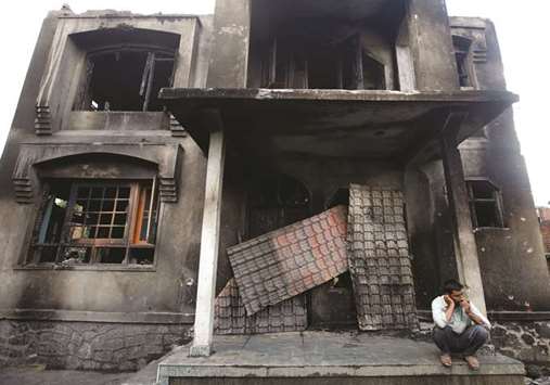 A man sits in front of a house which was damaged after a gun battle between security forces and militants in Redwani, in south Kashmiru2019s Kulgam district, yesterday.