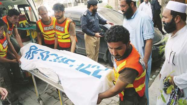 Rescue workers move the body of Ikramullah Gandapur, a candidate of the PTI, who was killed in a suicide attack in the northwestern province of Khyber Pakhtunkhwa, outside hospital morgue in Dera Ismail Khan, yesterday.
