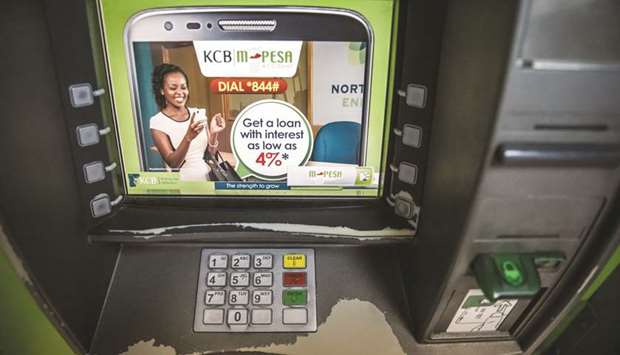 A KCB Bank Kenya ATM displays M-Pesa banking service information outside a bank branch in Mombasa (file). KCBu2019s net interest income jumped 10% in the first quarter while profit rose 14%.