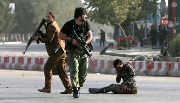 Afghan security forces arrive as an injured man sits on the ground at the site of a blast in Kabul on Sunday.