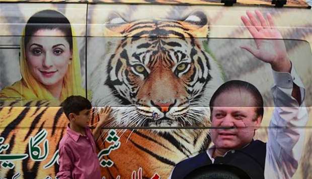A boy stands in front of a van decorated with pictures of former prime minister Nawaz Sharif and his daughter Maryam Nawaz  outside the election campaign office in Rawalpindi on Sunday. Pakistan holds the general election on Wednesday.