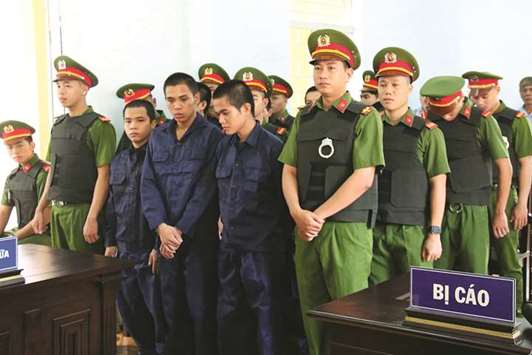 Detained protesters flanked by police stand before a court in Binh Thuan yesterday during their conviction for participating in a violent protest last June over a draft law on special economic zone.