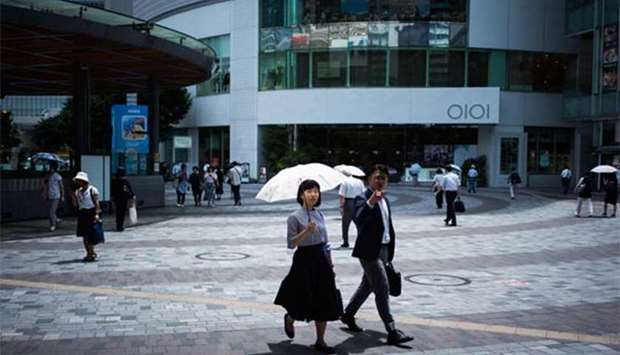 A woman holds an umbrella as she walks along a street in Tokyo on Monday. A deadly heatwave has toppled temperature records across Japan.