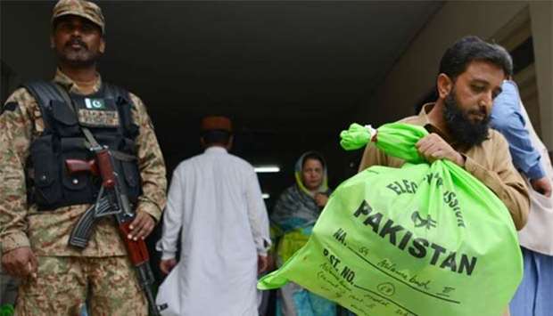 A Pakistani soldier stands guard as an official carries election materials at a distribution centre in Islamabad on Tuesday. Pakistan will hold its general election on July 25.