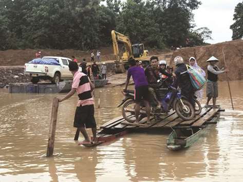 People use a makeshift ferry to cross the swollen Xe Khong river due to flash flooding in Sanamxai, Attapeu province, yesterday.