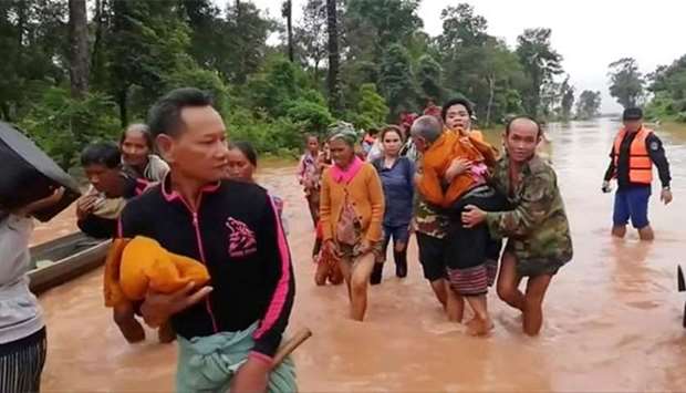 People walk through flooded area after being brought to safety by boat in Sanam Xay district, Attapeu province, after a hydropower dam under construction in southern Laos collapsed.