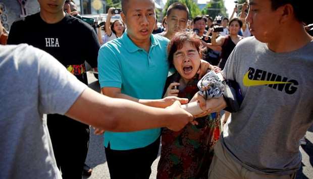 A woman is detained by security personnel outside the US embassy in Beijing